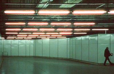 Side view of person walking on illuminated escalator