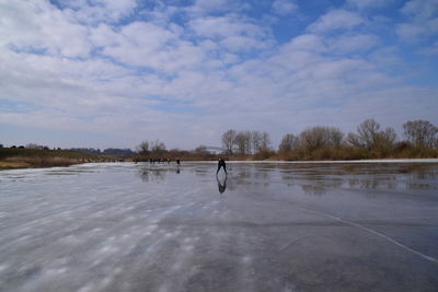 Man skating on frozen lake against sky.