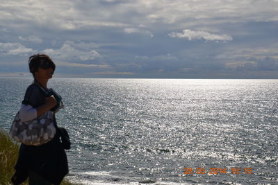 Boy standing in sea against sky