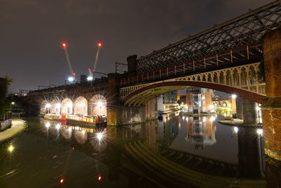 Illuminated bridge long exposure over river in manchester against sky at night