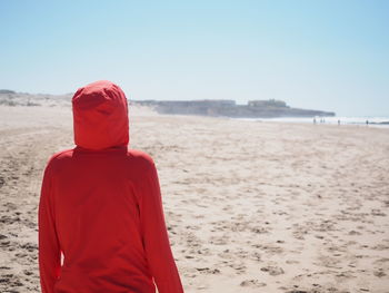 Rear view of woman on beach against sky