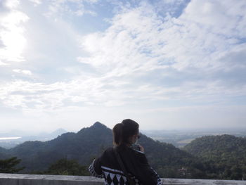 Rear view of woman looking at mountain against sky