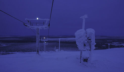 Snow covered land against sky at night