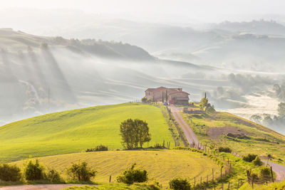 House on a hill in a hilly rural tuscan landscape with morning mists in the valley