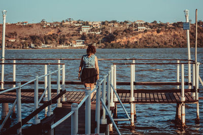 Woman standing on pier over sea