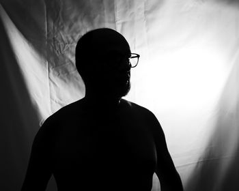 Silhouette man standing against curtain