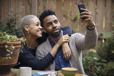 Couple taking selfie while sitting at table in backyard