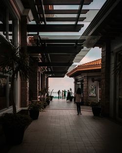 Rear view of people walking on footpath amidst buildings