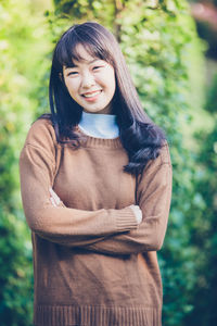 Portrait of smiling young woman standing against plants