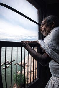 Side view of man looking at river against sky