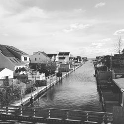 Canal amidst buildings in city against sky