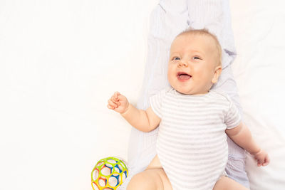 Portrait of cute baby boy lying against white background