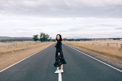 Full length of woman standing on road against sky