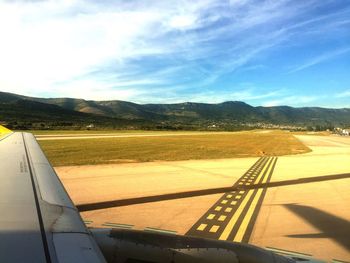 Road leading towards mountains against cloudy sky