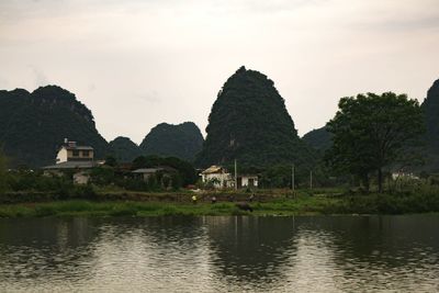 Built structure by lake and buildings against sky