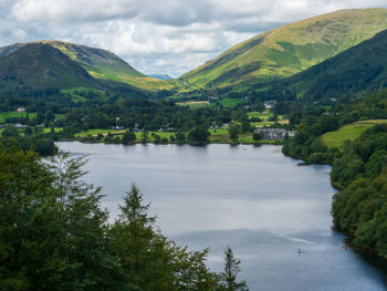 Scenic view of river by mountains against sky