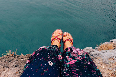 Low section of woman on rock by sea