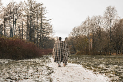 Rear view of man walking on snow covered land