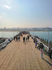 High angle view of people on footbridge over river against sky