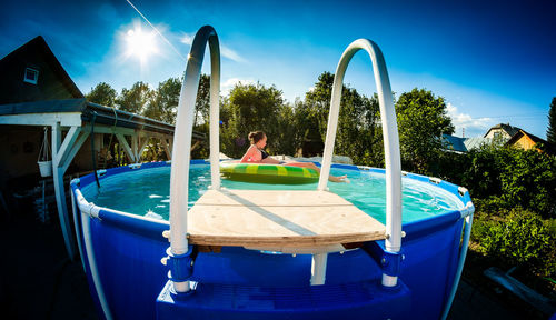 Girl with inflatable ring floating on wading pool at tourist resort