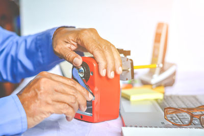 Cropped hands of businessman using pencil sharpener