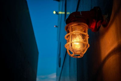 Low angle view of illuminated light bulb on wall