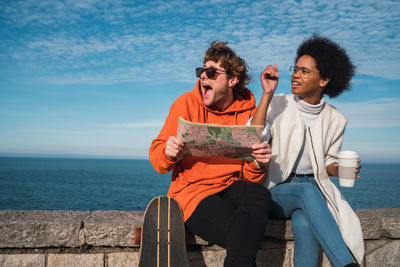 Friends sitting on shore against sea