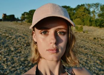 Portrait of young woman wearing cap on field