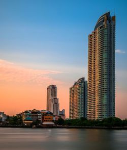 Modern buildings against sky during sunset in city