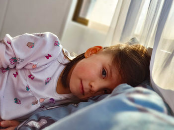 Portrait of cute girl lying on bed at home