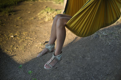 Low section of woman relaxing in hammock on field