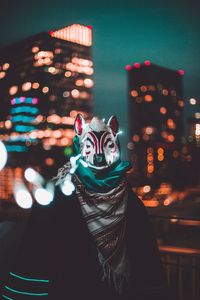 Person wearing animal mask standing outdoors at night