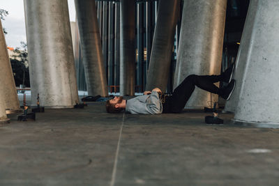 Man lying on street by columns in city