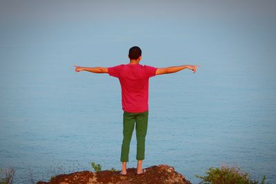 Rear view of man standing in sea against clear sky