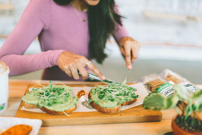 Midsection of woman having sandwich at home