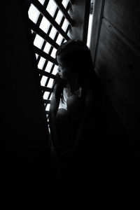 Woman looking through window at home