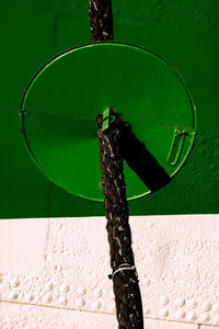 Close-up of rope tied up on wooden post against wall