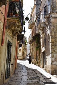 Rear view of people walking on street amidst buildings in city