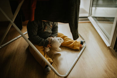 Low section of toddler sitting on floor at home