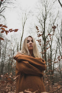 Woman standing by tree in forest