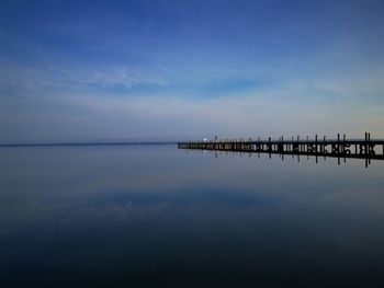 Wooden posts in sea against sky