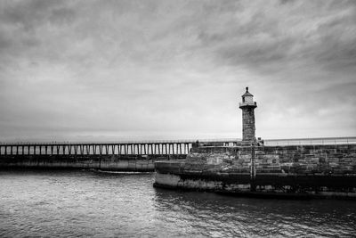 Lighthouse by sea against sky