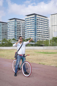 Full length of man standing by bicycle against building