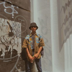 Portrait of young man standing against wall