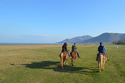 Rear view of three people riding horses