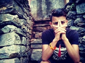 Portrait of young man standing against wall