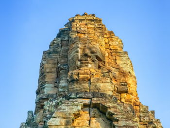 Low angle view of rock formations against clear blue sky