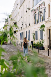 Rear view of woman standing by buildings in city