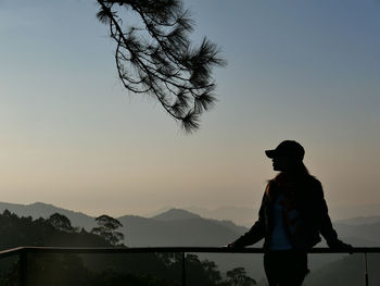 Silhouette man standing by lake against sky during sunset