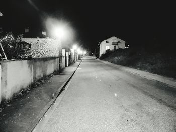 Surface level of empty road along buildings at night